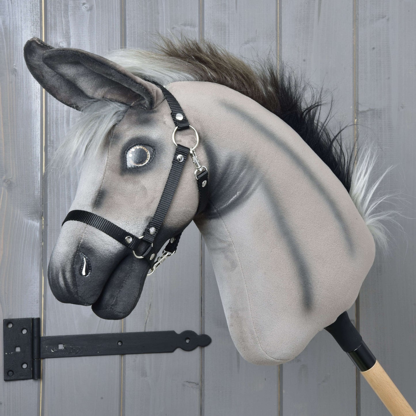 Hobby Horse osel Olin s černou ohlávkou od Hobby Horse LarDen se šedým plyšovým tělem, huňatou hřívou a černou ohlávkou, nasazený na dřevěné tyči, ideální na hraní nebo vystavení na jakémkoli pozadí.