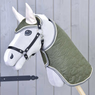 Set Olivetti od Hobby Horse LarDen tvoří šedý Hobby Horse se zelenou prošívanou dekou a uzdečkou, černou ohlávkou, bílými ušima a stylovými doplňky, zobrazený před světle šedou dřevěnou stěnou.