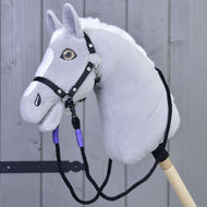 Otěže Basic Lila od Hobby Horse LarDen, ručně vyrobené z polypropylenového lana, zobrazené se šedým plyšovým Hobby Horse s bílou hřívou a černou uzdečkou, upevněným na dřevěné tyči před šedým dřevěným plotem.