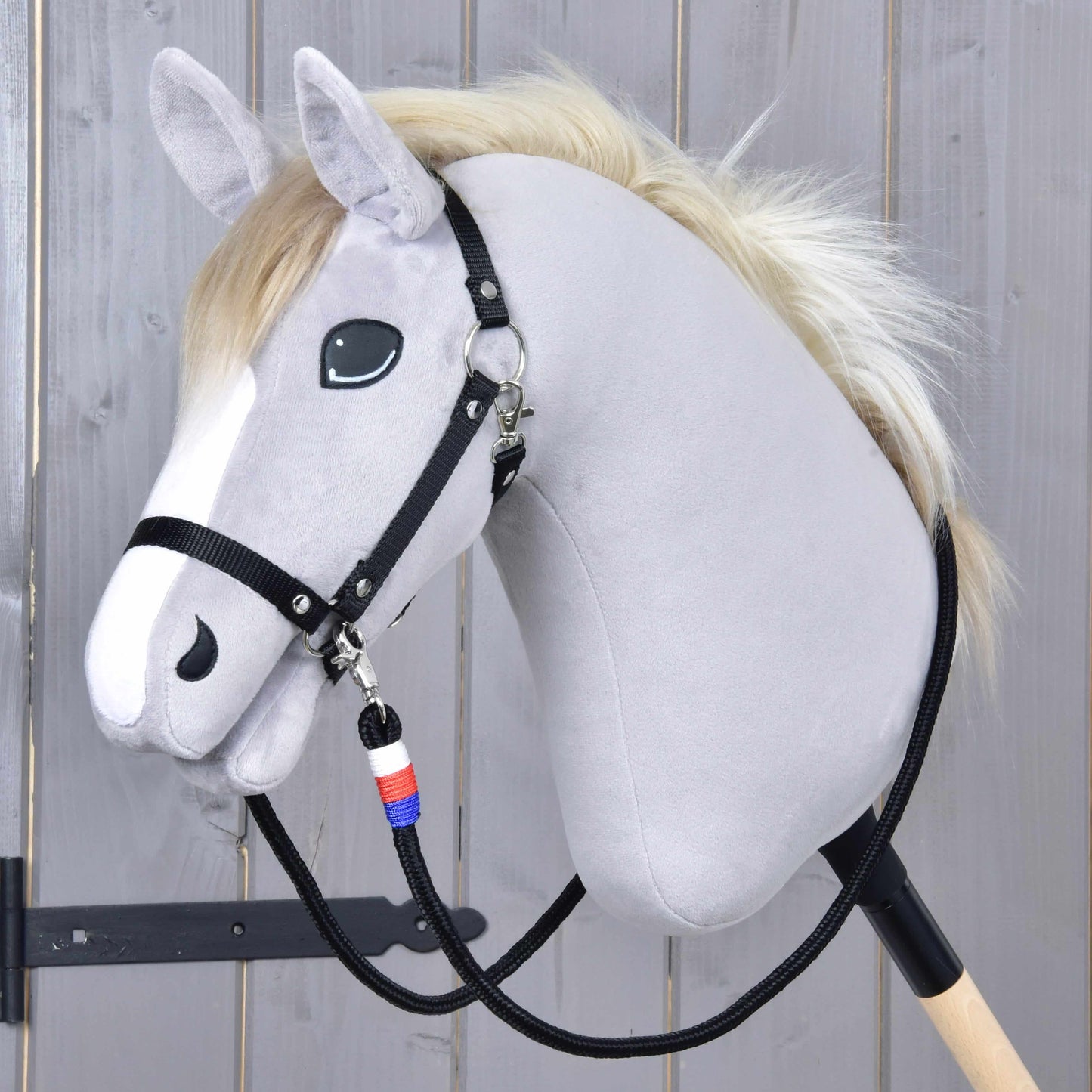 Otěže Emblem CZ od Hobby Horse LarDen na plyšovém Hobby Horse se světle šedou hlavou, černou uzdečkou, bílou hřívou a na dřevěné tyči; součástí jsou ručně vyráběné otěže „Reins Emblem CZ“ s modrým, bílým a červeným přívěskem.