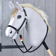Otěže Emblem od Hobby Horse LarDen na šedém plyšovém Hobby Horse s bílou hřívou, černou uzdečkou a ručně vyráběnými polypropylenovými otěžemi na dřevěné tyči, na pozadí světlých dřevěných prken.