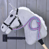 Hobby Horse - pletené vodítko Pinkie-Blue od Hobby Horse LarDen na šedém plyšovém Hobby Horse s černou uzdečkou, bílou hřívou a pleteným růžovo-tyrkysovým vodítkem, zavěšeném na dřevěné stěně. Tyč je součástí.