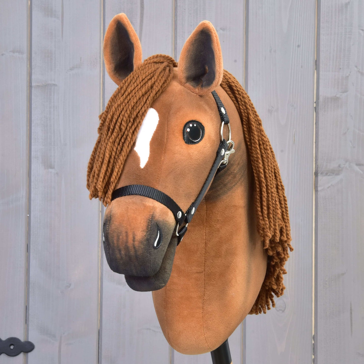 Hobby Horse LarDen Pippa s designem kaštanové klisny, hnědou přízovou hřívou, černou ohlávkou a bílou skvrnou na čele, zobrazená na světlem dřevěném pozadí.