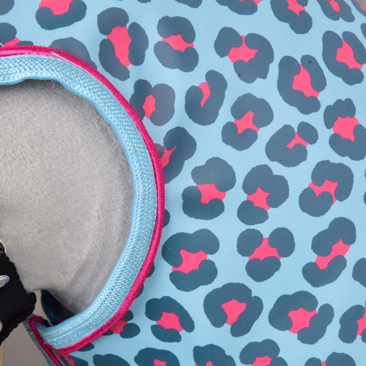 Detailní záběr na Pláštěnku Blue Leopard od Hobby Horse LarDen se světle modrou látkou, tmavě modrým a růžovým leopardím vzorem a světle modrým lemováním – ideální na vyjížďky za každého počasí.