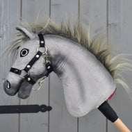 Hobby Horse Prestige s černou ohlávkou, velikost XS od Hobby Horse LarDen, šedá plyšová hlava Hobby Horse inspirovaná elegancí sportovního koně anglického teplokrevníka. Má výraznou vyšívanou tvář, divokou hřívu a bezpečně upevněnou černou ohlávku, je nasazená na dřevěné tyči. Na dřevěném pozadí, ideální pro nápaditá dobrodružství ve skákání.