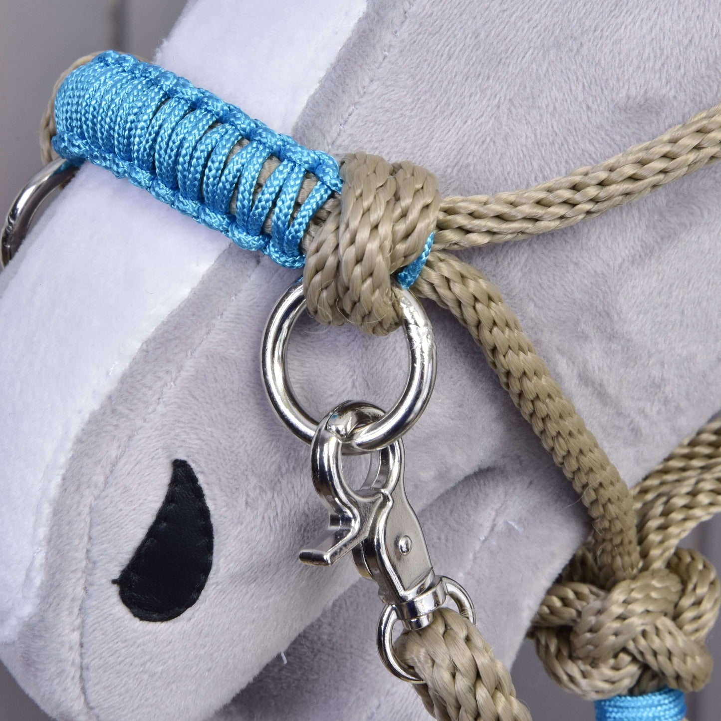 Detail plyšové šedé hlavy Hobby Horse LarDen s Provazovým setem Nature Blue, s modro-béžovou ohlávkou s kovovým kroužkem a karabinou, černým vyšívaným okem, bílým čenichem a připevněnými ladícími otěžemi.