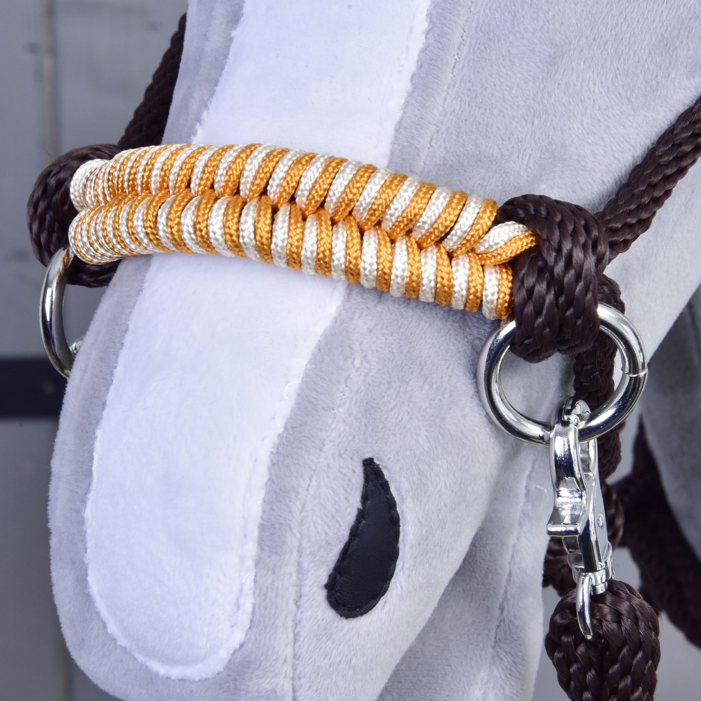 Provazový set Orange, detail plyšového obličeje Hobby Horse LarDen s bílým čenichem, černou nozdrou a bílo-zlatou ohlávkou s lesklými kovovými kroužky a ladícími hnědými otěžemi.
