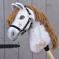 Hobby Horse Rufus s černou ohlávkou od Hobby Horse LarDen s ručně vyrobenou bíle skvrnitou látkovou hlavou, hnědou přízí jako hřívou, knoflíkovýma očima a černou ohlávkou na dřevěné tyči, zobrazený na pozadí šedého dřeva.