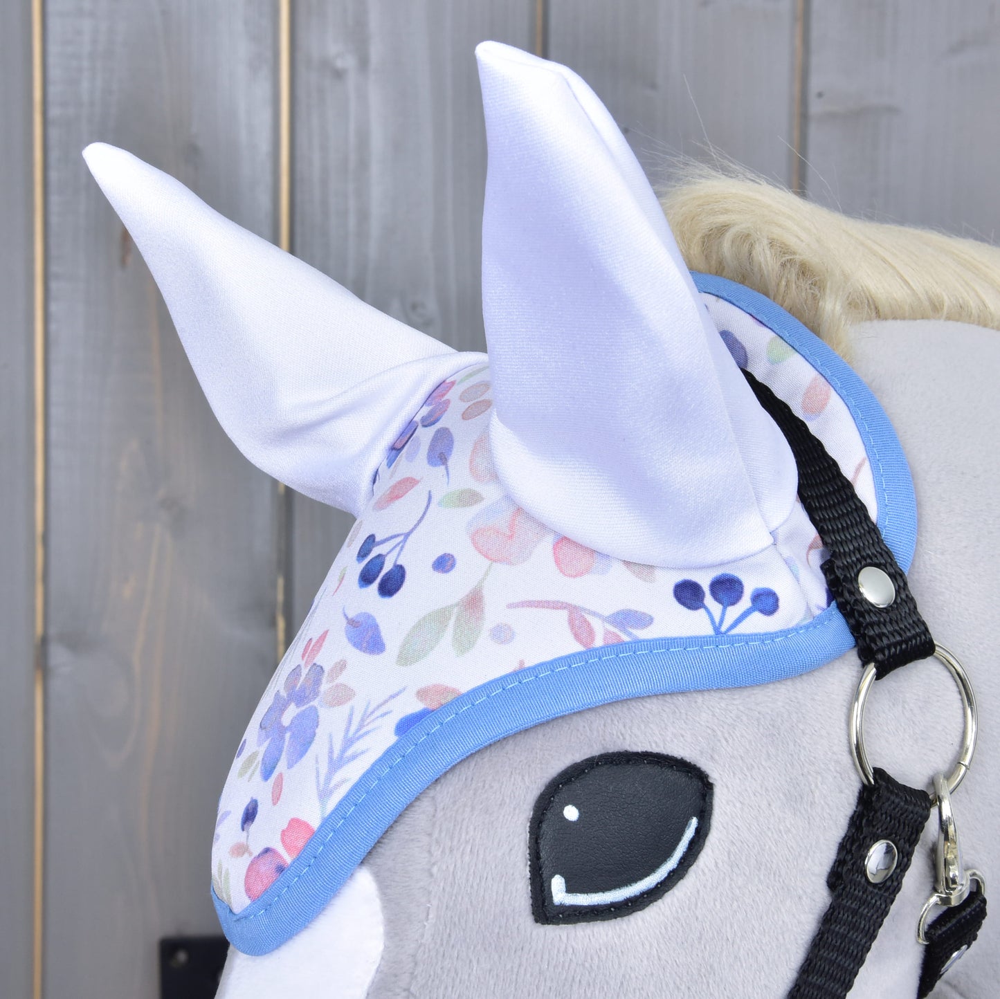Detail Set Vanessa NEW od Hobby Horse LarDen: hlava plyšového Hobby Horse s pastelovou květinovou čabrakou s jemnými bílými ušima, zobrazená na dřevěném pozadí.