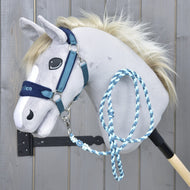 Set LarDen Exclusive Blue od Hobby Horse LarDen, plyšový Hobby Horse na tyči se světle šedou hlavou, modrou ohlávkou s fleecovým nánosníkem a pleteným vodítkem na dřevěném pozadí.