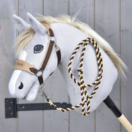 Set LarDen Exclusive Braun od Hobby Horse LarDen, plyšový šedý Hobby Horse s bílou hřívou, hnědou uzdečkou, fleecovým nánosníkem a pletenými provazovými otěžemi na dřevěné tyči, na pozadí šedé dřevěné stěny.