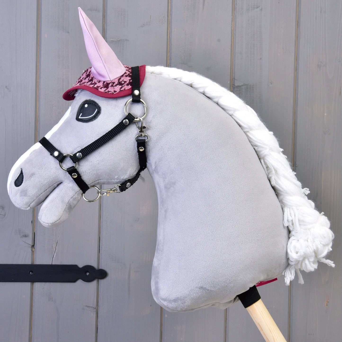 Set slavnostní Bordeaux od Hobby Horse LarDen s plyšovým šedým Hobby Horse s bílou hřívou, růžovými ušima a červenou uzdečkou, s elegantní dekou, na dřevěné tyči na pozadí šedých dřevěných prken.