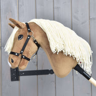 Hobby Horse Smart s černou ohlávkou od Hobby Horse LarDen s krémovou přízovou hřívou a dřevěnou tyčí, vystavený na dřevěné stěně se svislými šedými panely.