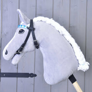 Uzdečka bez nánosníku tyrkysová se 2 čelenkami (vel. M) od Hobby Horse LarDen na šedém plyšovém hobby horse s bílou hřívou a dřevěnou tyčí, zobrazená před světle šedou dřevěnou stěnou.