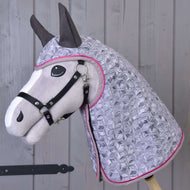 Hobby Horse LarDen Pláštěnka Valentine je plyšový Hobby Horse s černou uzdečkou a světle fialovou prošívanou kapucí s geometrickým vzorem a růžovým lemováním, zobrazený na pozadí dřevěných panelů.
