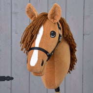 Hobby Horse Wendy s černou ohlávkou od Hobby Horse LarDen má hnědou plyšovou hlavu, spletenou hnědou hřívu z příze, bílý pruh na čenichu a černou ohlávku, inspirovanou ryzkou klisnou, a je zobrazená na šedém dřevěném pozadí.