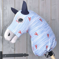 Hobby Horse ochranný oblek Andromeda (Lycra) od Hobby Horse LarDen v modro-bílých pruzích s červenými potisky humrů zakrývá hračkového koně, který má černé oči, tmavě modré uši a světle šedý čumák, na pozadí dřevěné stěny.