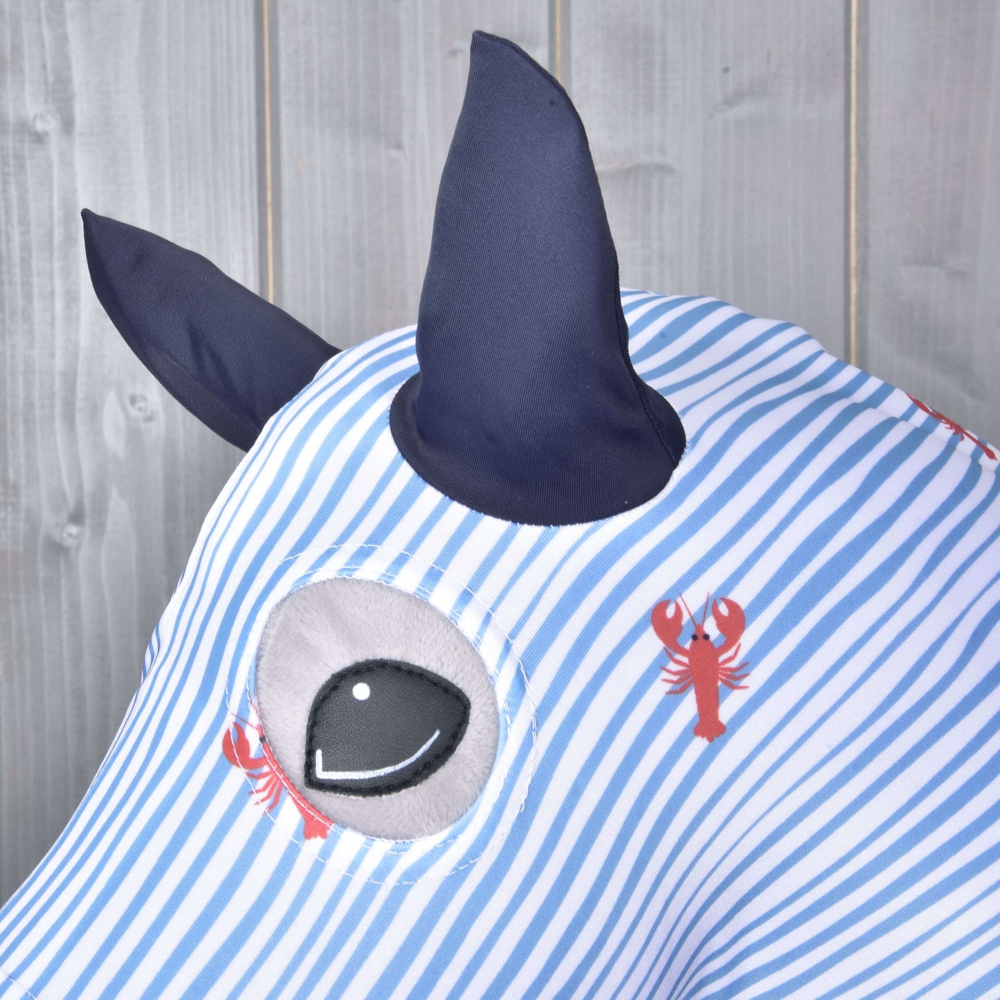 Detailní záběr na Hobby Horse ochranný oblek Andromeda (Lycra) od Hobby Horse LarDen ukazuje modro-bílé pruhy, měkkou látku PES a Lycra, tmavě modré rohy, velké kreslené oko a červené potisky humrů – ideální pro hravou ochranu Hobby Horse.