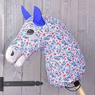 Hobby Horse LarDen Hobby Horse ochranný oblek Avatar (Lycra) s látkovou hlavou s modrým a červeným květinovým vzorem, modrými plstěnými ušima, šedou hřívou a pratelným obalem. Je nasazený na dřevěné tyči před dřevěným panelovým pozadím.