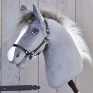Hobby Horse Beauty s černou ohlávkou od Hobby Horse LarDen má šedou plyšovou hlavu hřebce s bílou hřívou na dřevěné tyči, zobrazenou na pozadí dřevěného plotu.
