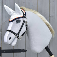 Čabraka Speedy od Hobby Horse LarDen na realistickém šedém hobby horse s černou uzdečkou, bílou hřívou a bílou čabrakou proti mouchám, nasazeném na dřevěné tyči před světle šedou dřevěnou stěnou.