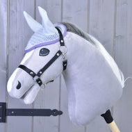 Světle šedý Hobby Horse s bílou hřívou, s černou uzdečkou a čabrakou háčkovanou Candy od Hobby Horse LarDen pro ochranu před hmyzem, umístěný před dřevěným panelovým pozadím.