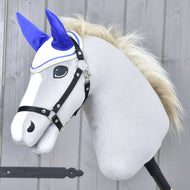 Hobby Horse LarDen se světle šedou plyšovou hlavou, bílým čenichem, černou uzdečkou a krémově zbarvenou hřívou, doplněný o čabraku Cream Pearl k ochraně proti hmyzu. Je nasazený na tyči a umístěný na dřevěném pozadí.