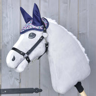 Čabraka Flower od Hobby Horse LarDen na plyšové hračce Hobby Horse se světle šedou hlavou, černou uzdečkou a třpytivou fialovo-stříbrnou čabrakou pro ochranu proti hmyzu, na dřevěném pozadí.
