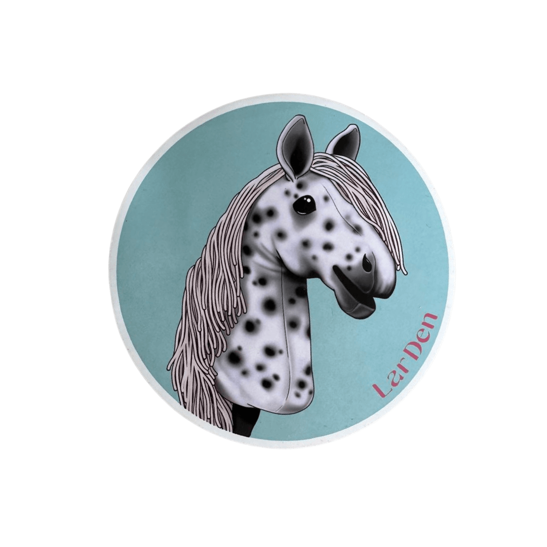 Ilustrace usmívajícího se černo-bílého Hobby Horse se šedou hřívou na modrém pozadí s růžovým textem „Landen“ – Set Stickers 5 od Hobby Horse LarDen, ideální pro fanoušky samolepek hobby horse.