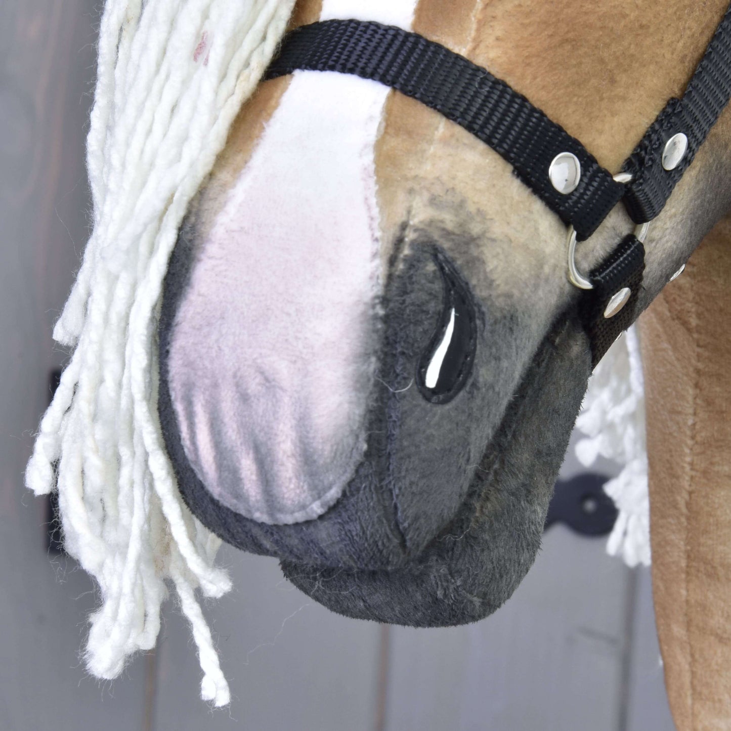 Detail ručně vyrobené Connie od Hobby Horse LarDen se světle hnědo-bílým obličejem, černou ohlávkou a bílou přízovou hřívou. Jsou vidět detailní stehy a textura látky.