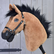Detail Hobby Horse Cookie s černou ohlávkou od Hobby Horse LarDen, s hnědým plyšovým koněm s černou hřívou a ohlávkou, lesklýma očima a šedým dřevěným pozadím.