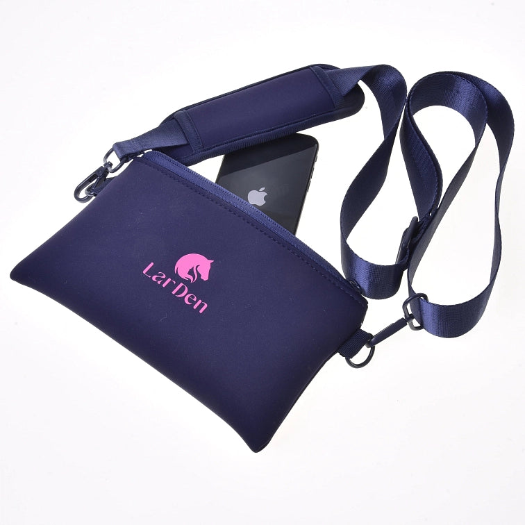 Tmavě modrá crossbody taška LarDen s růžovým logem, zobrazená s nastavitelným popruhem a černým smartphonem částečně zasunutým v přihrádce na zip – ideální na přenášení nezbytností na vaši další akci Hobby Horsing – na bílém pozadí.