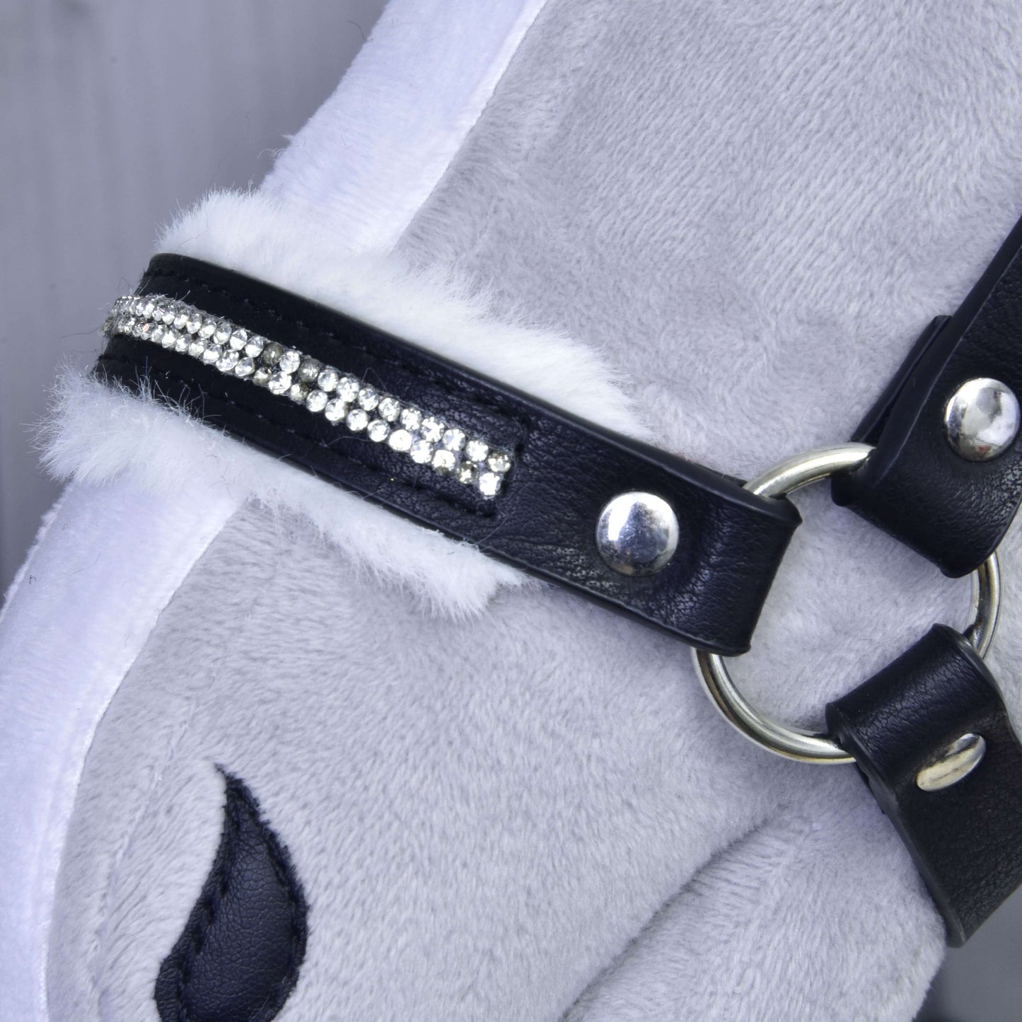Detail plyšové hlavy koně s Ohlávkou s beránkem z koženky Espresso od Hobby Horse LarDen, s bílým lemem z umělé kožešiny, třpytivými kamínky, stříbrným kováním a částí vyšívaného oka.