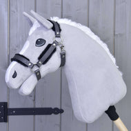 Ohlávka s beránkem z koženky Graphite Full od Hobby Horse LarDen na dřevěné tyči, opřená o světle šedou dřevěnou stěnu, se šedou plyšovou hlavou s bílou hřívou, černou uzdečkou a ohlávkou z koženky.