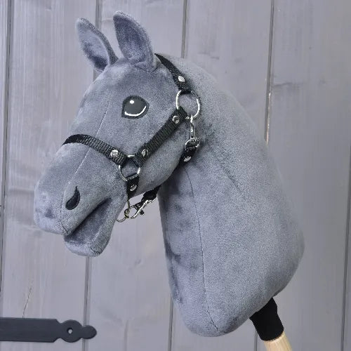 Hobby Horse Build your horse od related_to_12441055625556 má tmavě šedou srst s jemnými odznaky na hlavě a je dodáván s černou uzdečkou, nasazený na dřevěné tyči a zobrazený před šedou dřevěnou stěnou.