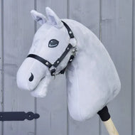 Build your horse, světle šedý vlastní Hobby Horse s černou uzdečkou na dřevěné tyči, zobrazený před šedou dřevěnou stěnou v elegantním stylu Black & White Mélange.