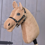 Hobby Horse Build your horse od related_to_12441055625556 s karamelově zbarvenou hlavou ze světle hnědé látky, černou uzdečkou a očima zvýrazněnými bílou barvou je nasazený na dřevěné tyči před šedou dřevěnou stěnou.