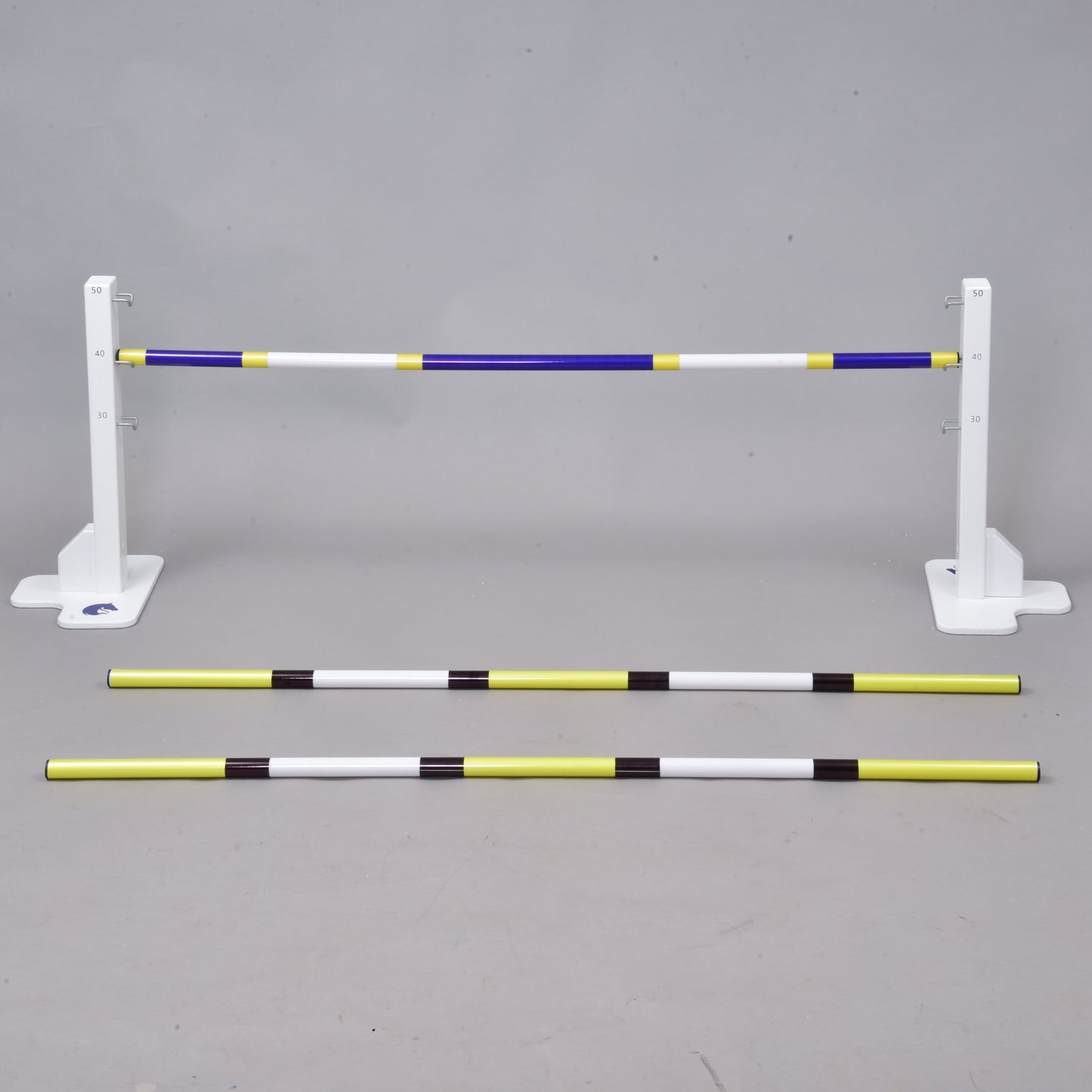 Set překážky kolmák 50 cm + 2 ks bariérky od Hobby Horse LarDen obsahuje tři pruhované tyče – dvě na zemi a jednu zvednutou – a poskytuje nastavitelnou překážku pro jezdecký trénink, dog agility nebo Hobby Horsing, vhodnou pro použití uvnitř i venku.