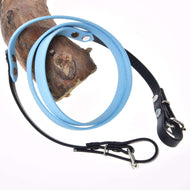 Otěže pogumované Light blue od Hobby Horse LarDen, se světle modrou a černou kůží, kovovou přezkou a designem inspirovaným uzdečkou, omotané kolem dřeva a zobrazené na bílém pozadí.