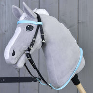 Šedý plyšový Hobby Horse s bílou hřívou, vybavený Kompletní uzdečkou bez nánosníku Light Blue od Hobby Horse LarDen, nasazený na dřevěné tyči a vyfotografovaný před šedou dřevěnou stěnou.
