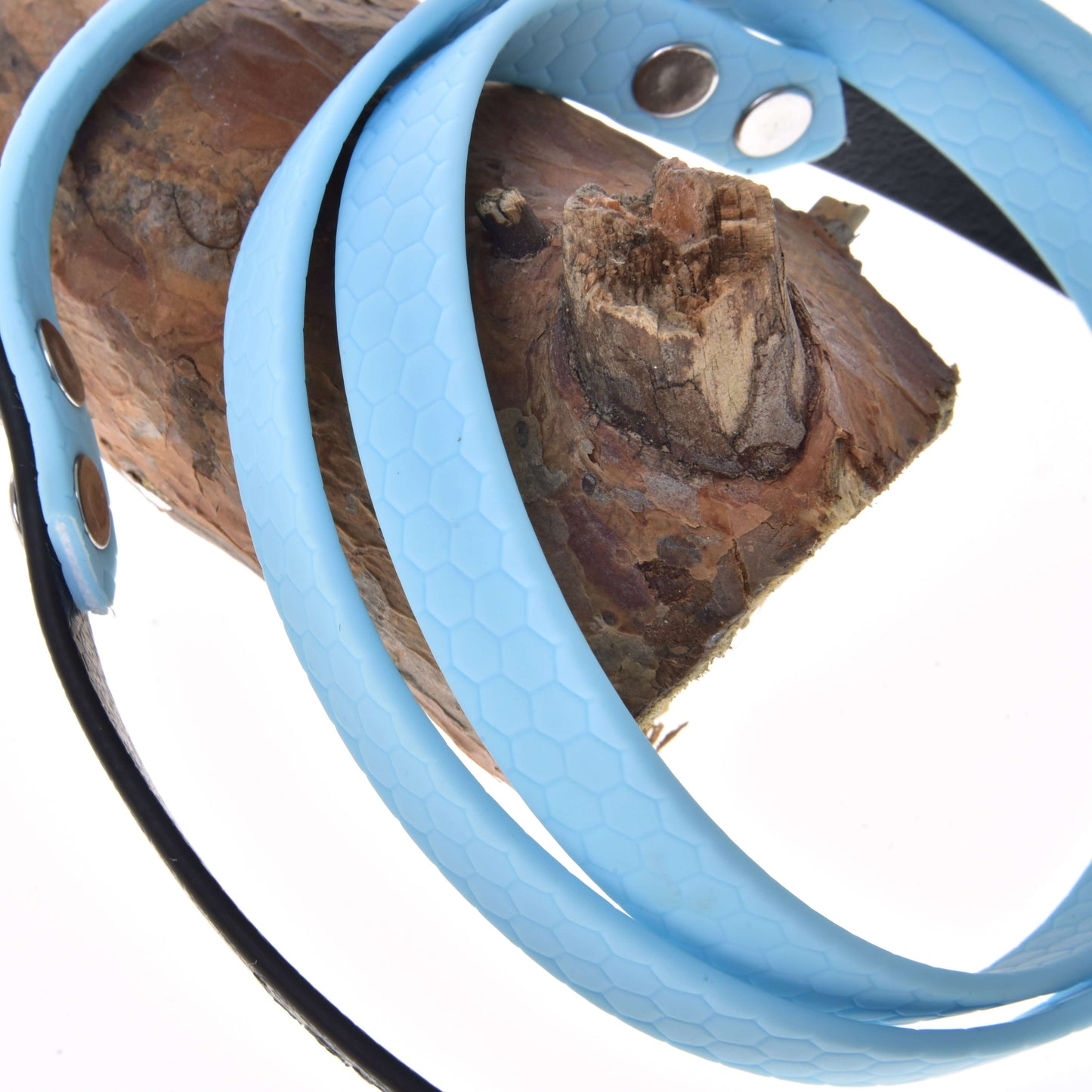 Detail Otěží pogumovaných Light blue od Hobby Horse LarDen s kovovými karabinami, přehozených přes hnědé dřevo na bílém pozadí.