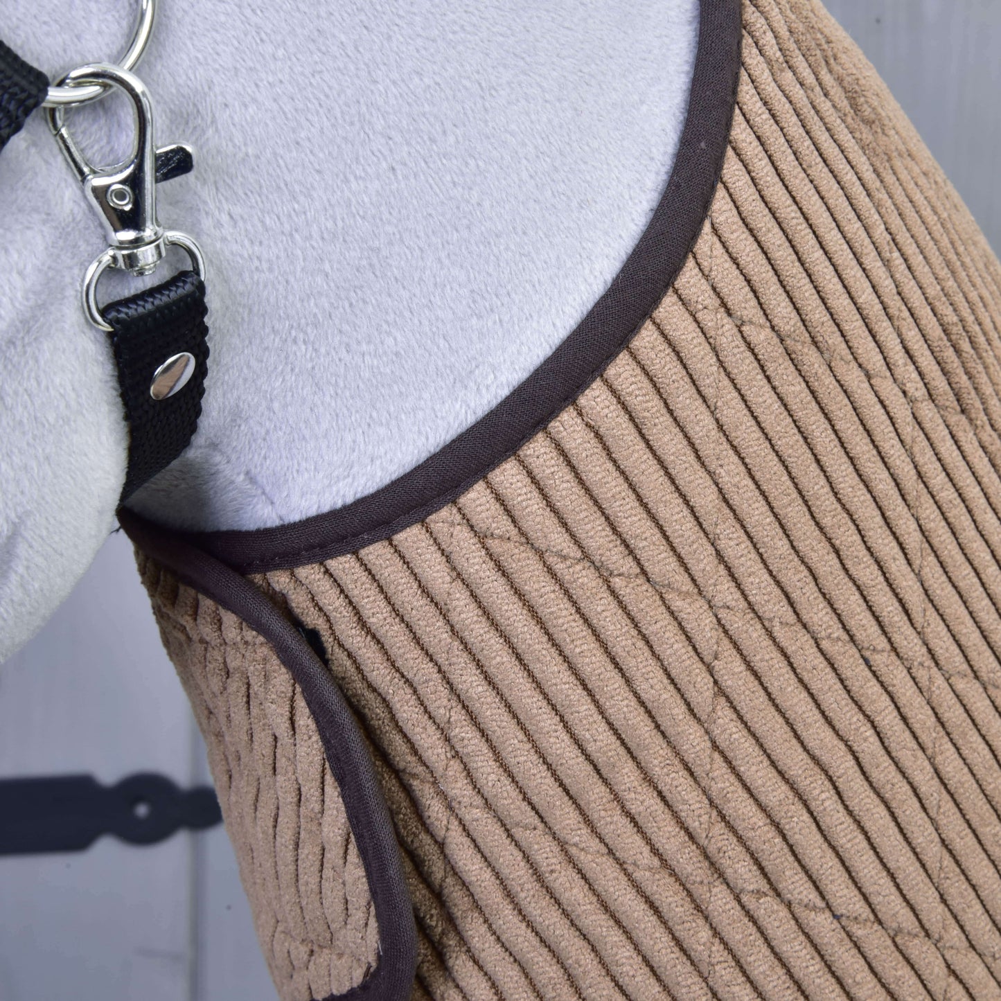Detail koně v Set Manchester Le Chocolate od Hobby Horse LarDen s prošíváním v pískové barvě, hnědým lemem a černou ohlávkou se stříbrným kováním. Elegantní design doplňuje částečně viditelnou bílou srst koně.