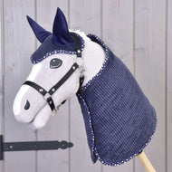 Hobby Horse LarDen Set Manchester Blue Star obsahuje šedého Hobby Horse s černou uzdečkou a otěžemi, tmavě modrou prošívanou deku a čabraku s bílým lemem, zobrazené na dřevěné tyči před světlým dřevěným obložením.