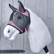 Maska proti hmyzu de Luxe Pink od Hobby Horse LarDen na šedém plyšovém Hobby Horse s růžovým lemováním a pratelnou maskou proti hmyzu, nasazeném na dřevěné tyči, na pozadí z dřevěných prken.