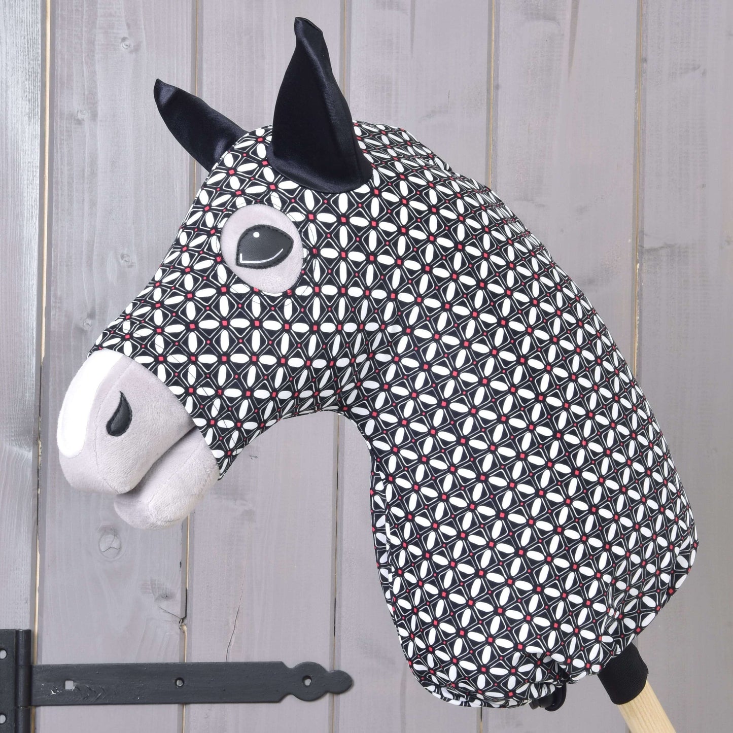 Hobby Horse ochranný oblek DeLuxe (Lycra) od Hobby Horse LarDen z černé, bílé a červené geometrické látky s černýma ušima a prošívanými detaily obličeje, zobrazený na pozadí světlých dřevěných panelů.