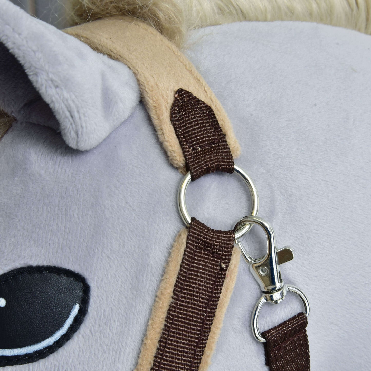 Detail plyšového koně s ohlávkou s beránkem LarDen Brown od Hobby Horse LarDen, s měkkým fleecovým nánosníkem a kovovým kroužkem s karabinou u ucha a oka. Hračka má světle šedý povrch a krémově zbarvenou hřívu.