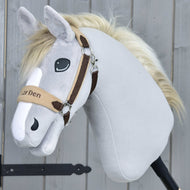 Hobby Horse LarDen Ohlávka s beránkem LarDen Brown se světle šedým plyšem, krémovou hřívou, béžovohnědou ohlávkou s měkkým fleecovým nánosníkem, vyšívanýma očima a přátelským výrazem na dřevěném pozadí.