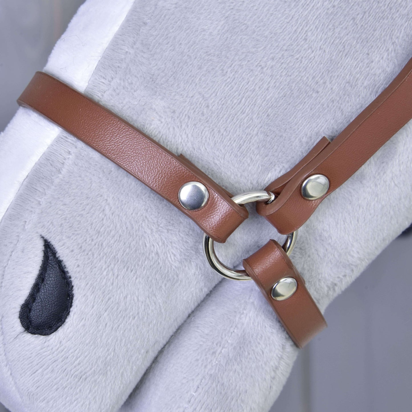 Detail šedé plyšové koňské hlavy s ohlávkou Ohlávka - hnědá koženka od Hobby Horse LarDen, se stříbrnými kroužky a cvočky. Je vidět černé vyšívané oko, perfektní doplněk do každé sbírky Hobby Horse.