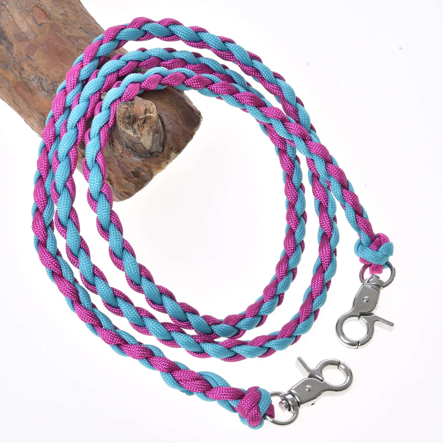 Otěže knitted pinkie blue od Hobby Horse LarDen z modrého a růžového polypropylenového lana s kovovými karabinami na obou koncích, stočené na bílém pozadí a přehozené přes hnědé dřevo.