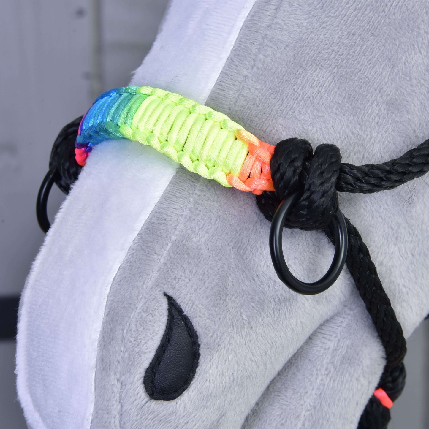 Detail šedého plyšového Hobby Horse od Hobby Horse LarDen s Parelkou Duha s kovovými kroužky a výrazným duhovým nánosníkem. Na obličeji je vidět černé označení ve tvaru kapky.